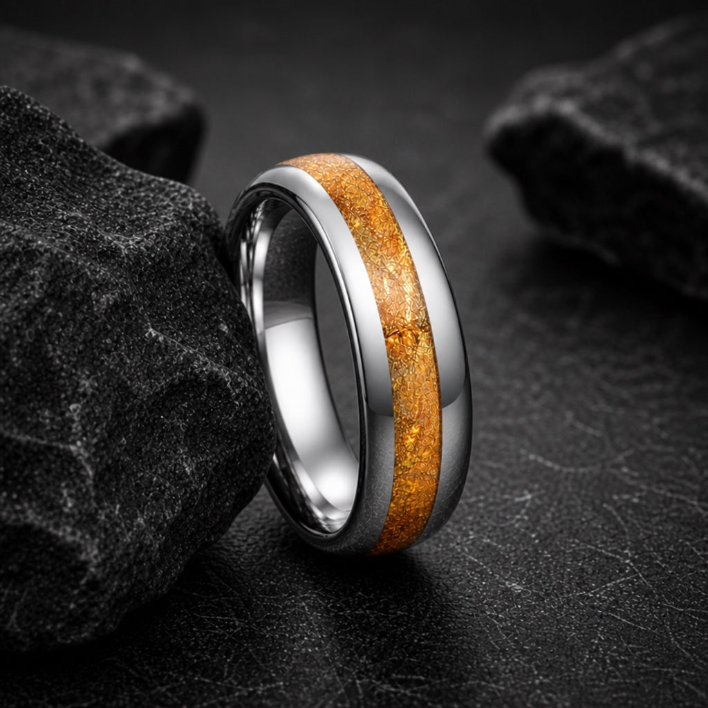The Amber ring resting against dark rock, silver body and gold foil visible