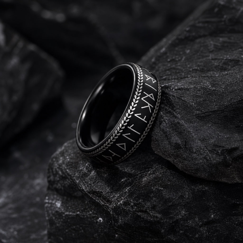 The Berserker ring resting against dark charcoal rock, Norse runes and braided borders visible
