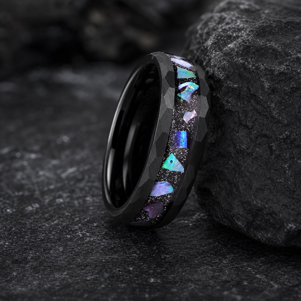 Magus ring full band on dark charcoal rock with hammered black rails and centred galaxy abalone visible