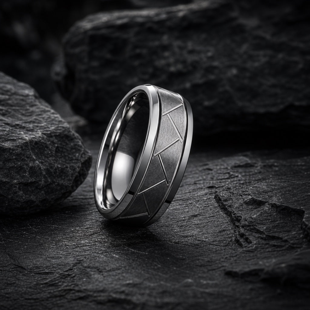 The Pioneer ring resting on dark charcoal rock, brushed gunmetal lattice face and bevelled rails fully readable