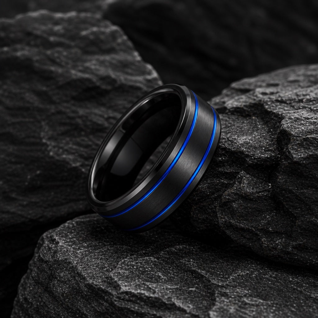The Sentry ring resting against dark rock, brushed black body and twin electric-blue grooves visible