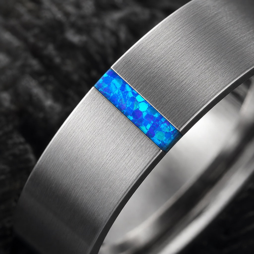Macro of the Serene ring's thin centred crushed blue opal channel in brushed silver tungsten on dark charcoal stone