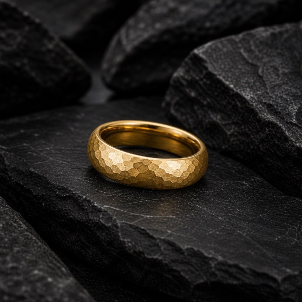 The Apollo ring resting against dark charcoal rock, hammered gold body visible