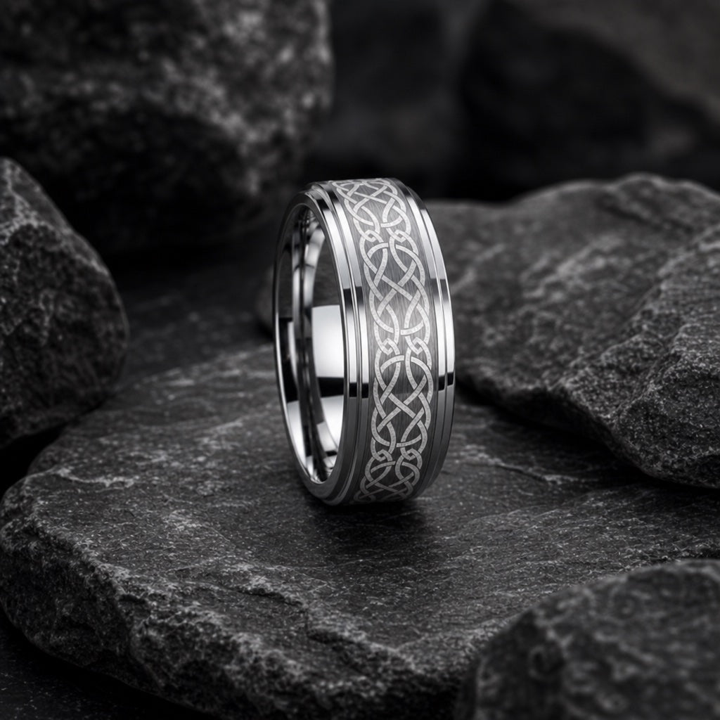 The Celtic ring resting against dark rock, silver body and knot engraving visible