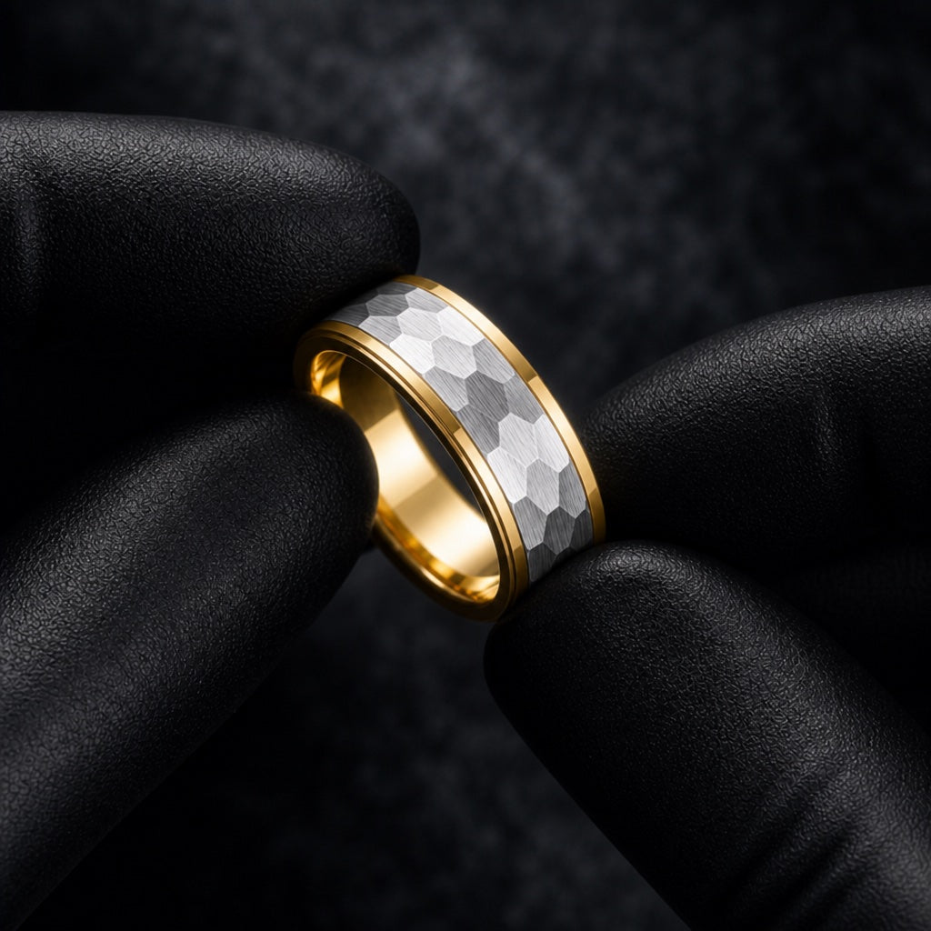 Gloved hands presenting the Lustre ring, yellow-gold stepped rails and hammered silver face visible