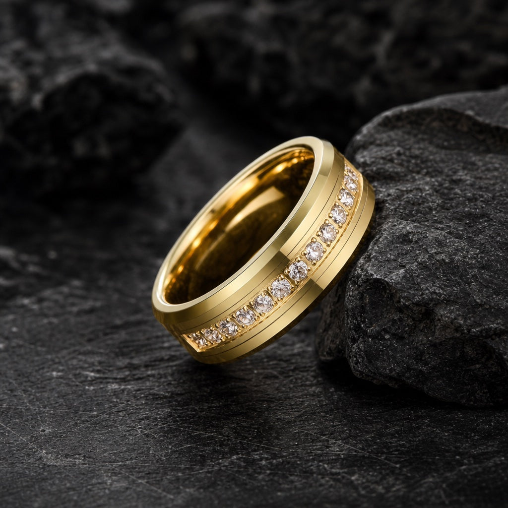 The Luxury ring resting against dark charcoal rock, polished yellow gold body and centred clear CZ channel visible