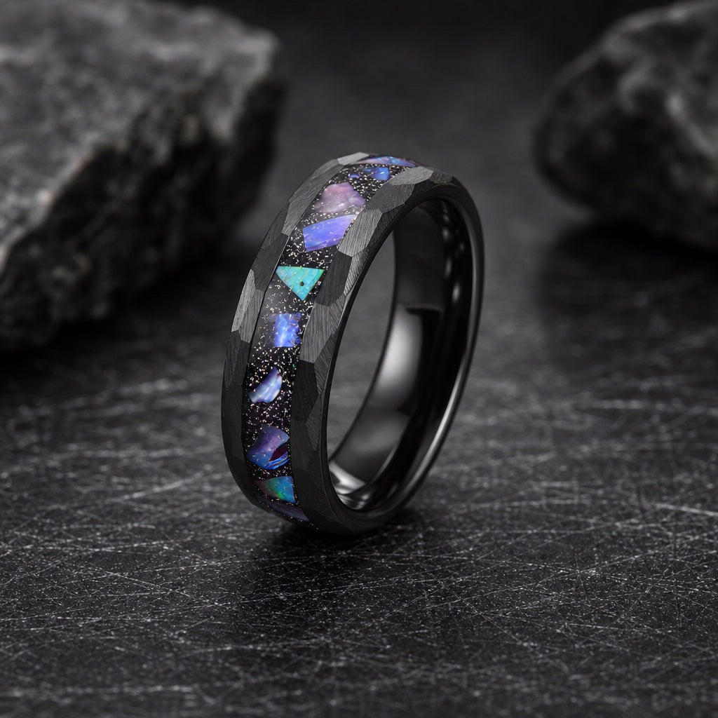 Magus ring showing hammered faceted black rails flanking the centred galaxy abalone channel on dark stone