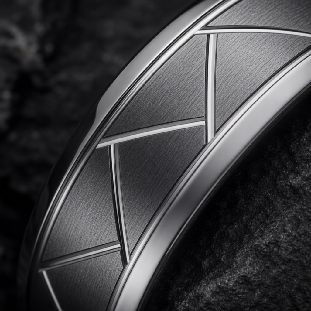 Macro of the Pioneer ring's polished geometric X diamond lattice engraving on brushed gunmetal face on dark charcoal stone