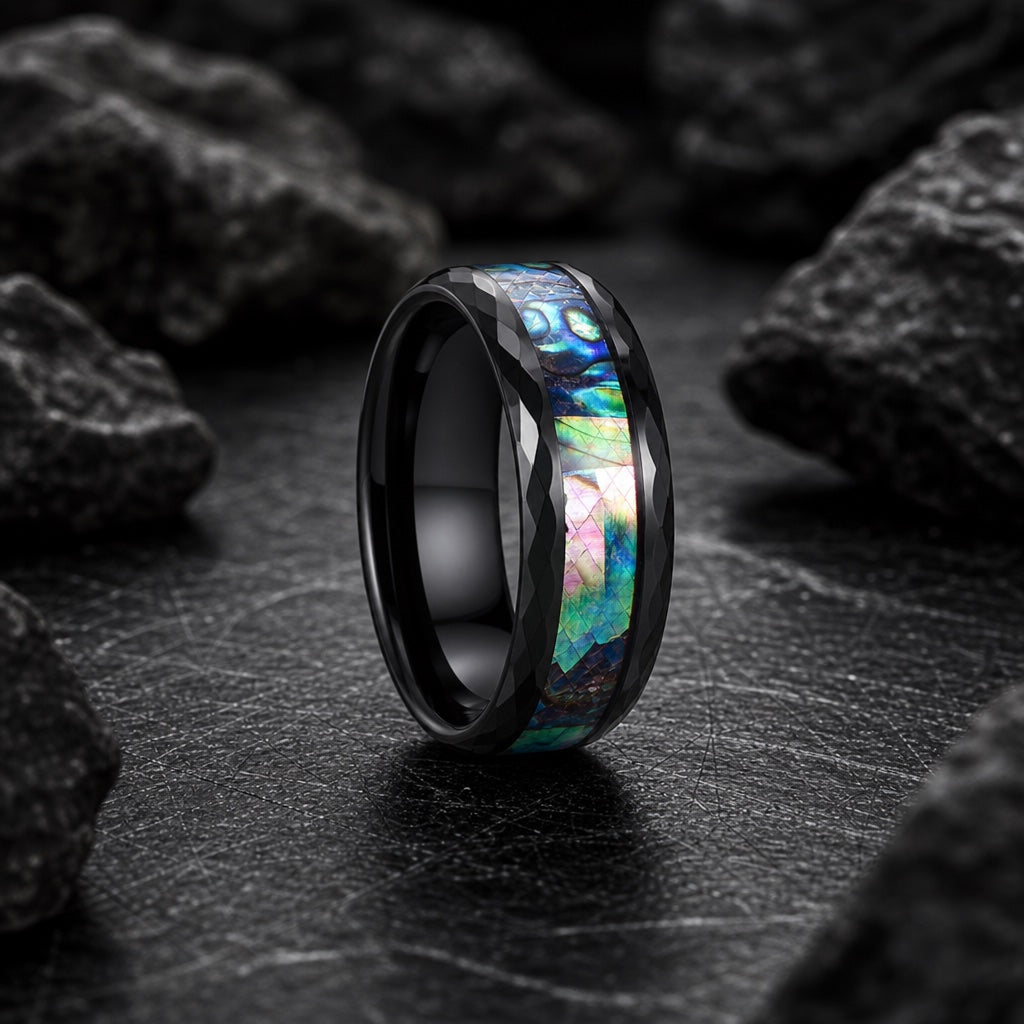Warlock ring showing faceted hammered black rails flanking the centred abalone channel on dark stone