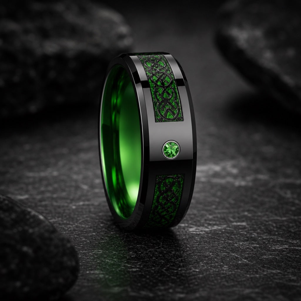 The Wildcard ring resting against dark rock, black body, twin green filigree and centre stone visible